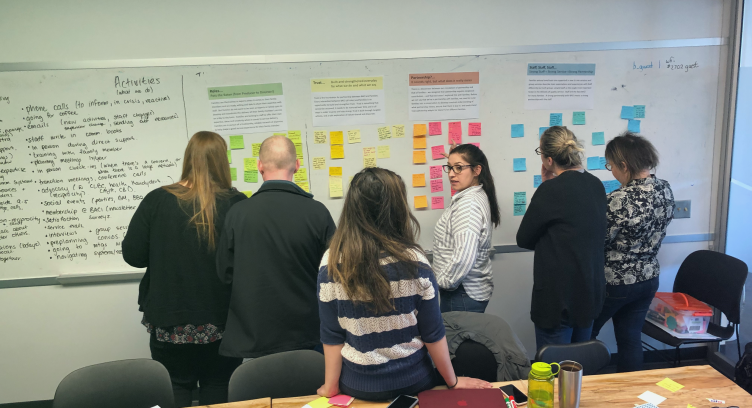 a group of people look at sticky notes on a white board