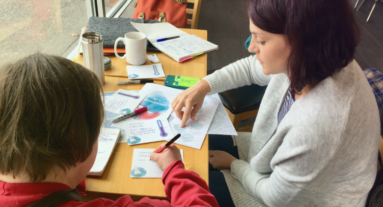 Two people are sitting at a table using and testing stitched services tools